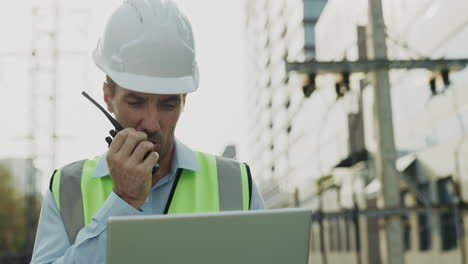 construction worker using walkie talkie and laptop