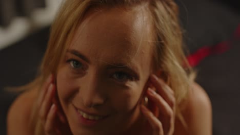 movimiento lento de cerca de una mujer atractiva vestida con lencería sexy acostada en la cama y sonriendo encantadoramente a la cámara