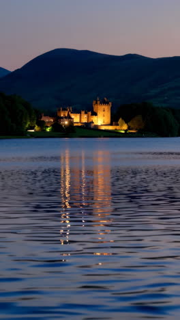 historic castle illuminated at dusk reflected in a serene lake