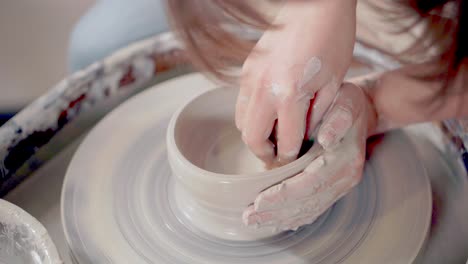 woman shaping a bowl on a pottery wheel