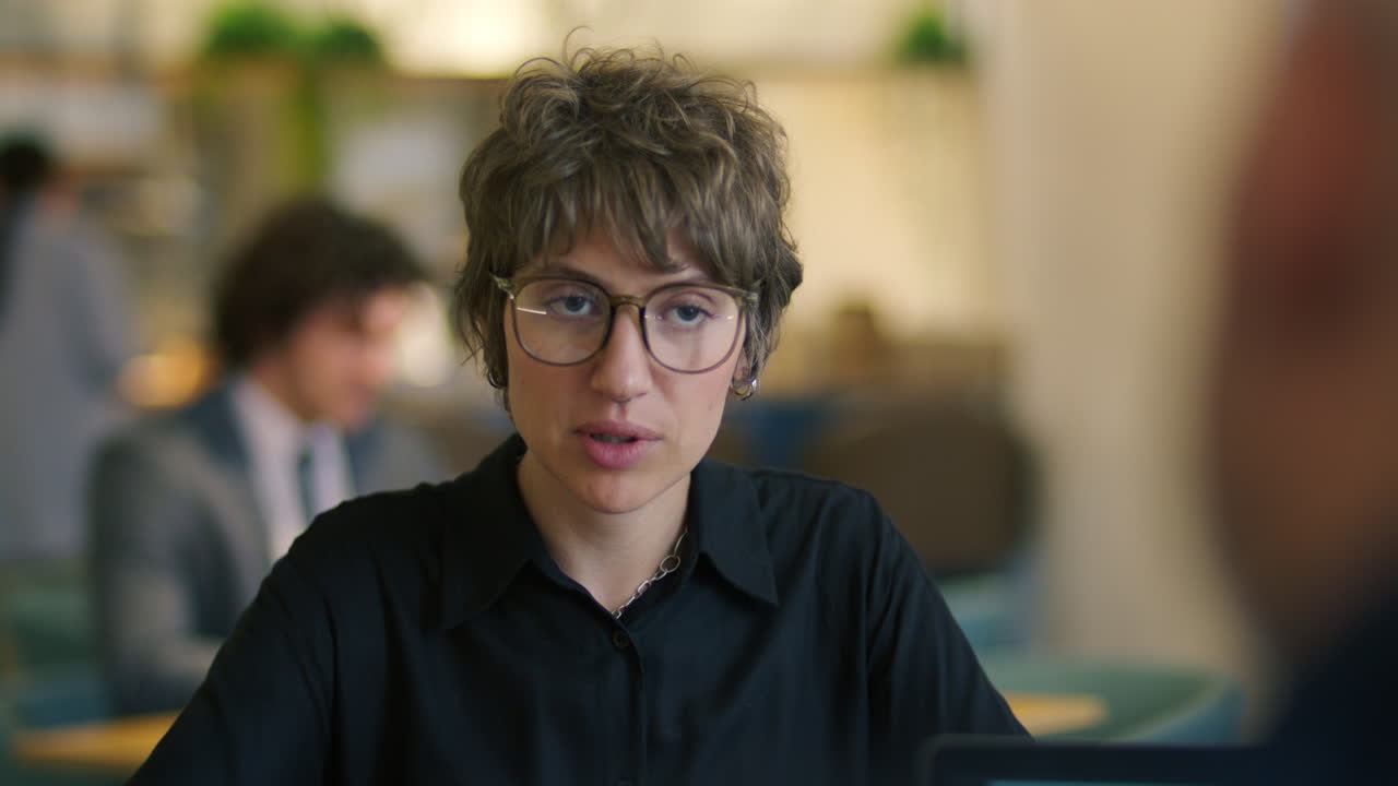 Young Woman Speaking with Business Partner during Meeting at Cafe