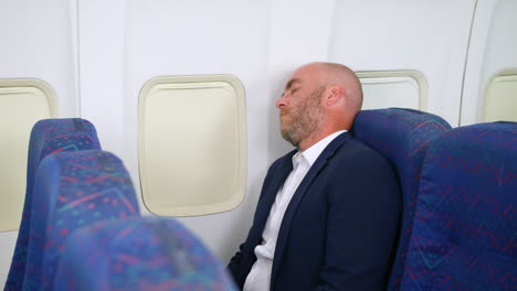 a business man relaxing asleep on a flight onboard a passenger airliner airplane whilst travelling