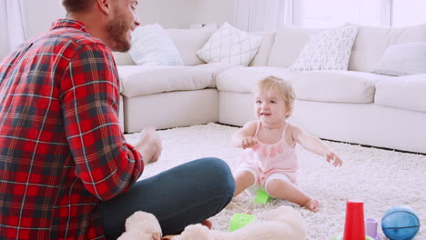 Junger-Vater-Spielt-Ukulele-Mit-Kleinkind-Mädchen-Im-Wohnzimmer