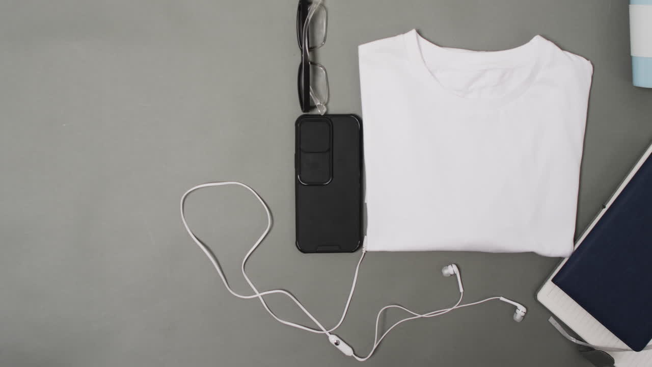 video de camiseta blanca, teléfono inteligente y auriculares con espacio de copia en fondo gris