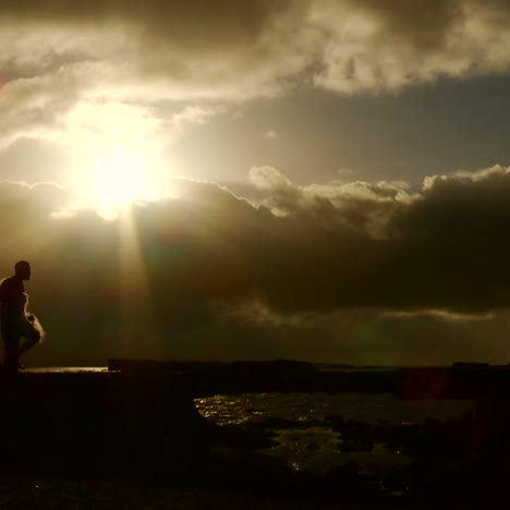 A-gorgeous-shot-as-a-fisherman-walks-in-front-of-the-sunset-with-his-net-in-slow-motion