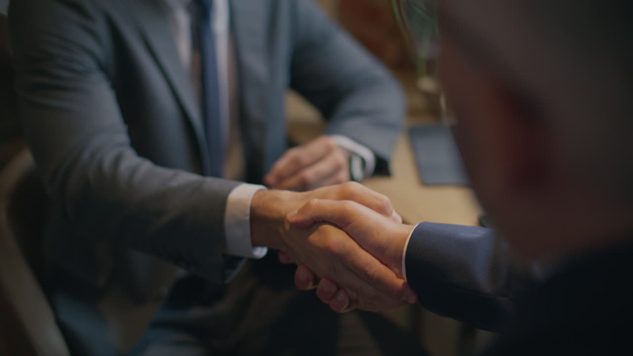 Close Up of Two Businessmen Shaking Hands after Discussion in Cafe