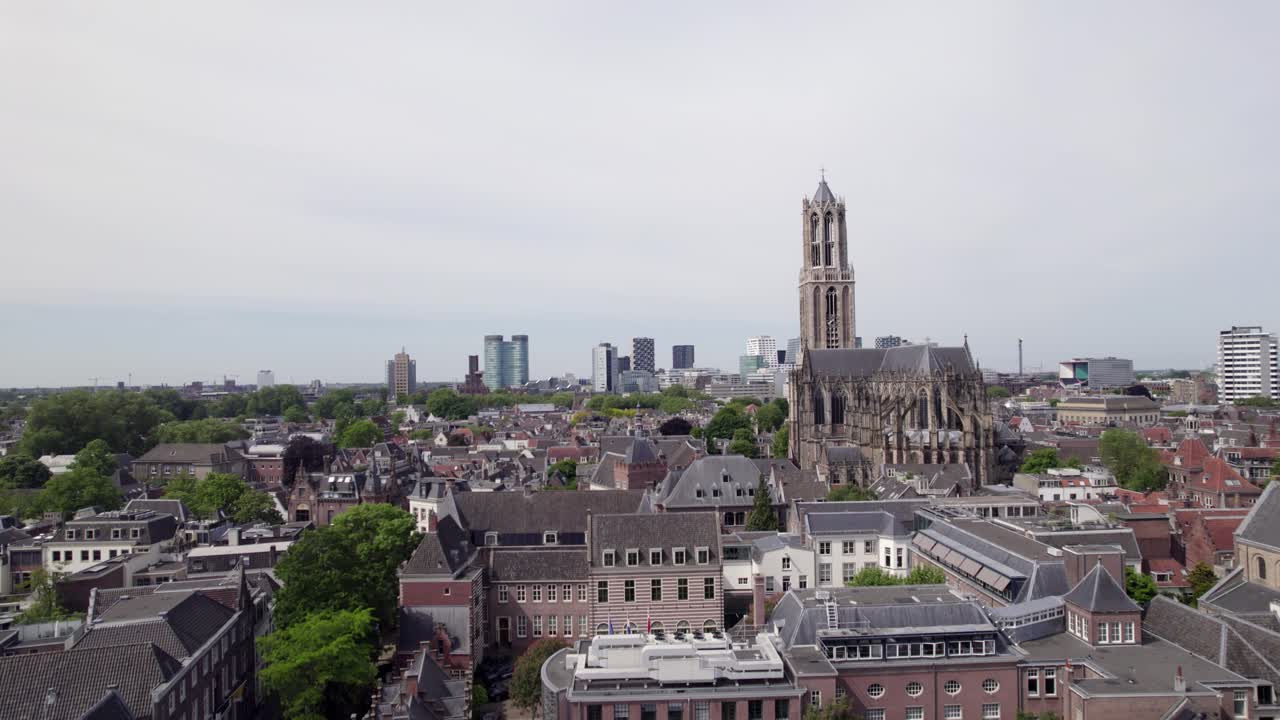 Aerial of gothic cathedral nave and De Dom church tower architecture among historic buildings in Utrecht city center. Dutch Holland religious tourist destination seen from above.