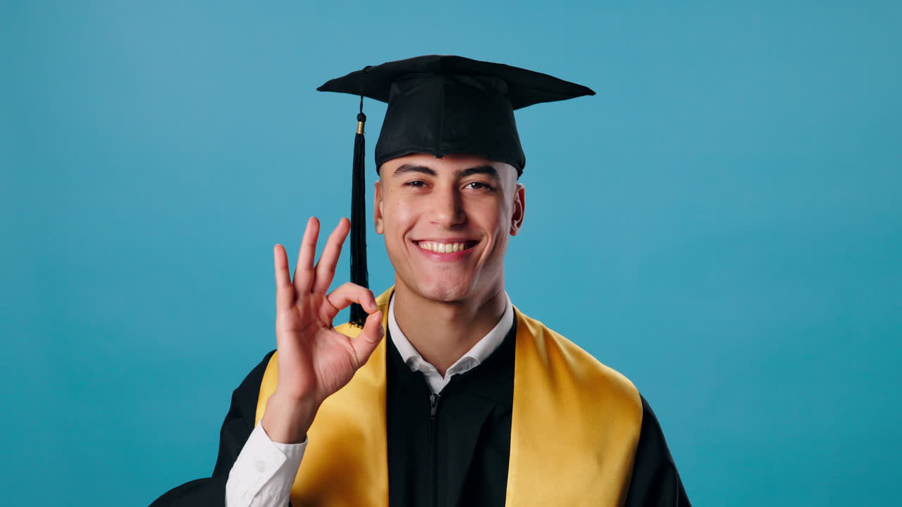 A graduate smiling and giving an OK sign
