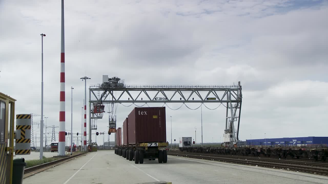 Cargo trucks at Rotterdam port under cranes on a cloudy day
