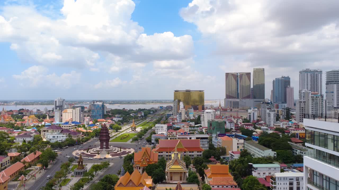 Aerial footage of Phnom Penh's vibrant skyline with towering skyscrapers under a clear blue sky. The drone video captures urban architecture, bustling streets, and serene river views