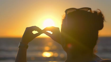 woman makes the sign of infinity with hands at sunset in 4k slow motion 60fps