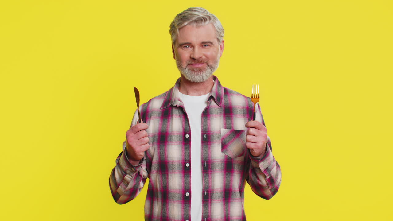 ⁇ 주린 남자가 저녁 식사를 위해 기다리고 있습니다. 불안함으로 식사 접시를 들고 식기 포크 칼을 들고 있습니다.