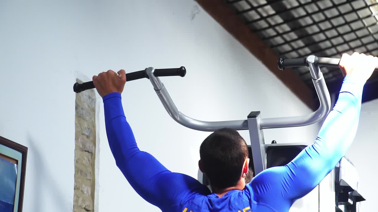 hombre haciendo deporte en una camiseta de ucrania, levantando el peso de su cuerpo para entrenar su espalda y brazos