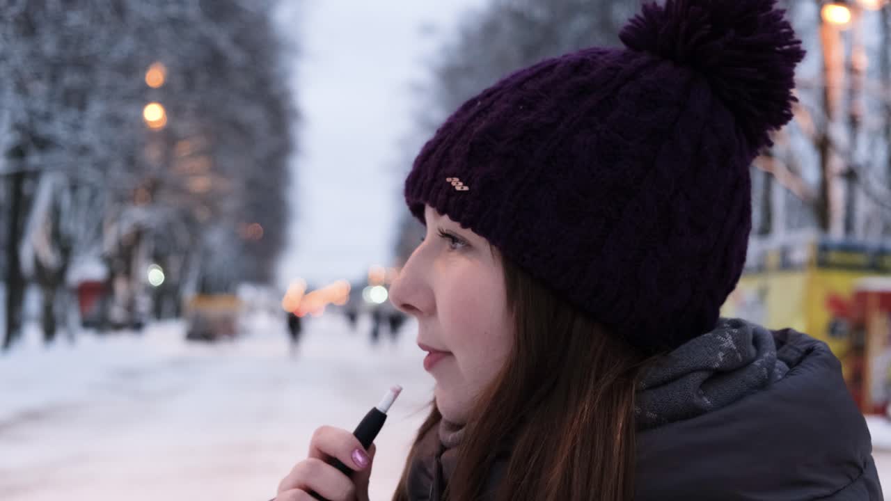 mujer vapeando en una ciudad nevada por la noche