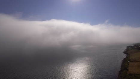 aerial of clouds drifting over a fjord