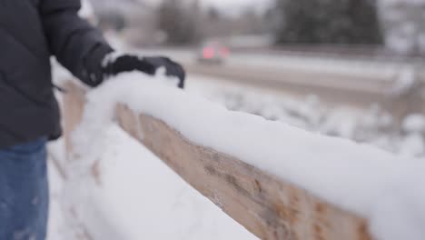 close up slow motion, hand of person with glove cleaning snow from wooden fence