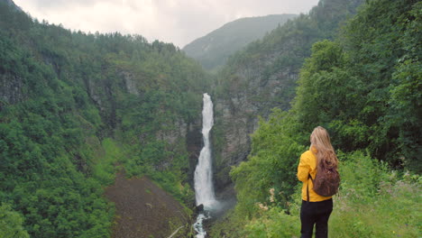 woman watching a waterfall in a norwegian forest