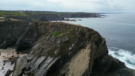 aerial orbits rugged rock headland cliff on ocean coast of portugal