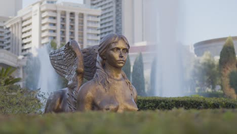a statue stands outdoors, framed by natural or urban surroundings.