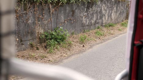 slowmotion of a tuk tuk (auto rickshaw) view in sintra, portugal with two cyclists passing by.