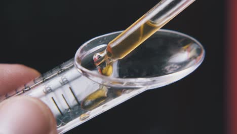 person drops water into measuring spoon on black background