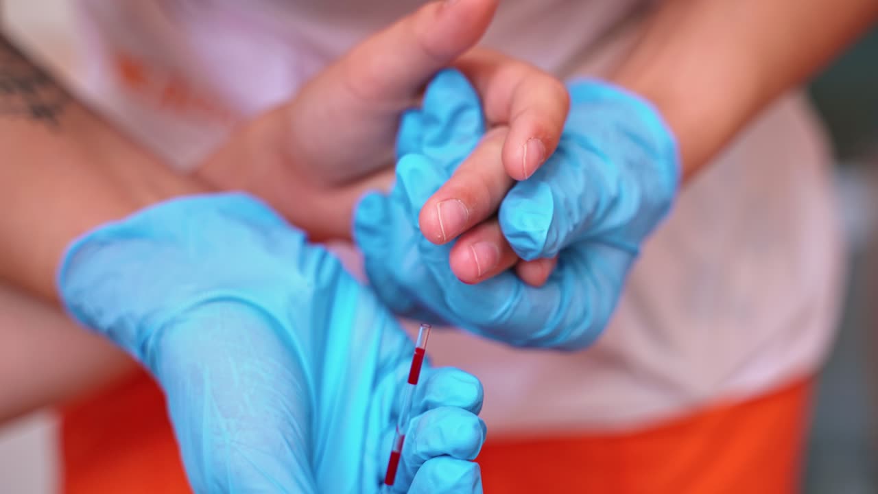 Nurse in blue gloves collecting blood. Close-up hands of a medical assistant taking blood sample from kid's finger.