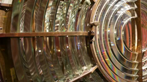 fresnel lens with brass structure, nautical lighthouse tower. detail of the glass lantern with rainbow spectrum. system of lamps and lenses to serve as a navigational aid. old sea searchlight beacon.