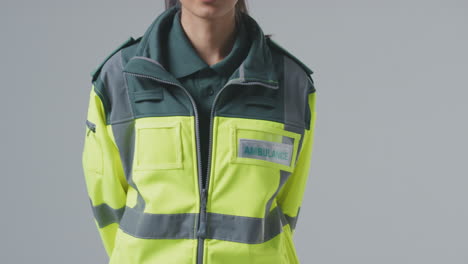 Full-Length-Studio-Portrait-Of-Serious-Young-Female-Paramedic-Against-Plain-Background