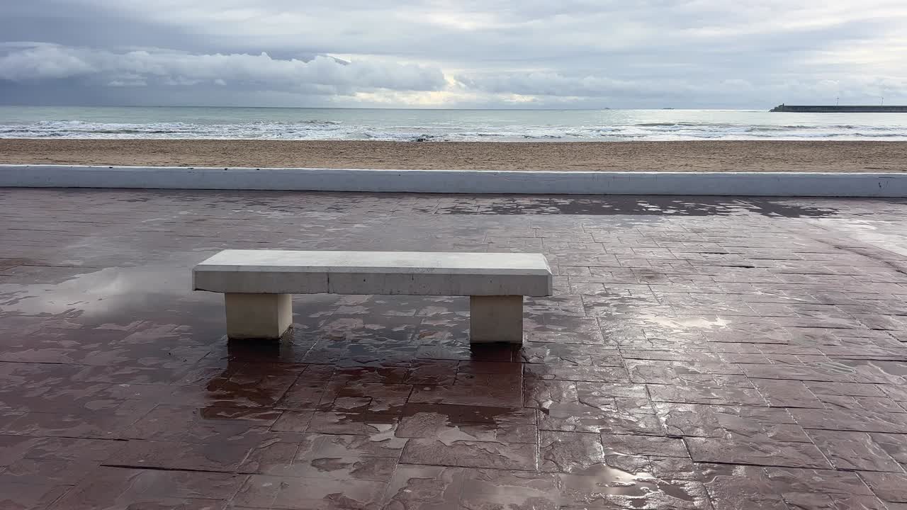 Fotografa il marciapiede bagnato accanto a una panchina di pietra