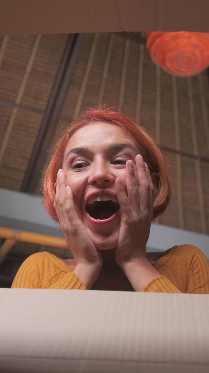 Young overjoyed caucasian woman opens cardboard box and looks inside