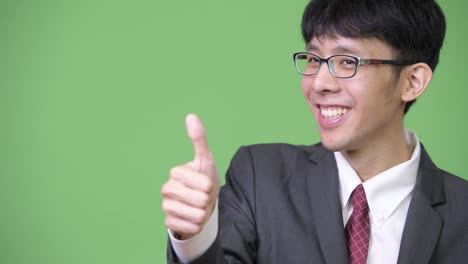 young happy asian businessman smiling while giving thumbs up