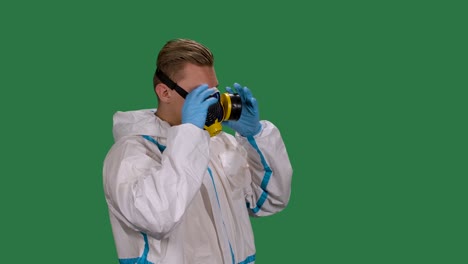vista lateral de un médico masculino en un traje de protección blanco y guantes quirúrgicos pone un respirador médico. pantalla verde, tecla de croma. cámara lenta