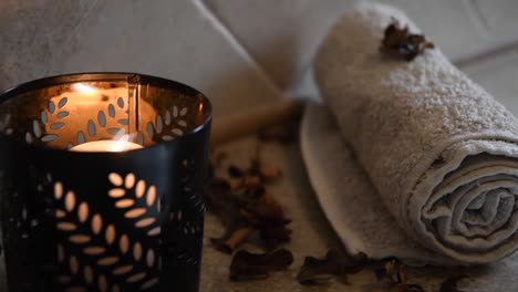 relaxing spa background with an hidden candle with flickering flame, some wooden petals and a towel