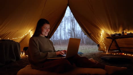 woman working on laptop in a cozy tent