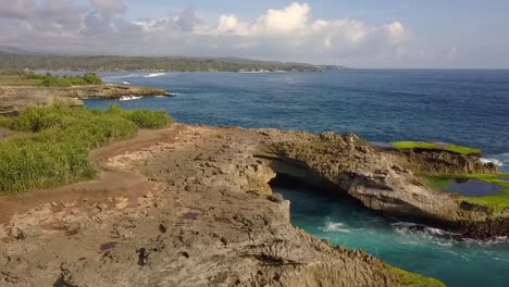 vista aérea suave vuelo volar hacia adelante drone disparó grandes olas del océano rompiendo en las rocas de la lágrima del diablo en lembongan indonesia