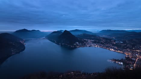 timelapse vespertino de la ciudad y el lago lugano desde monte bre, suiza mientras la ciudad se ilumina
