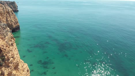 Picturesque-coastal-Limestone-cliffs-bordering-Algarve-Idyllic-ocean---Aerial-fly-over-panoramic-reveal-shot