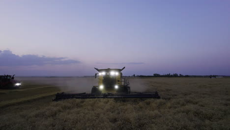 aerial pullback of approaching combine harvester harvesting wheat at twilight