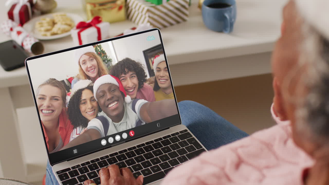animación de una mujer afroamericana en el sombrero de santa en una llamada de video portátil con la familia en navidad