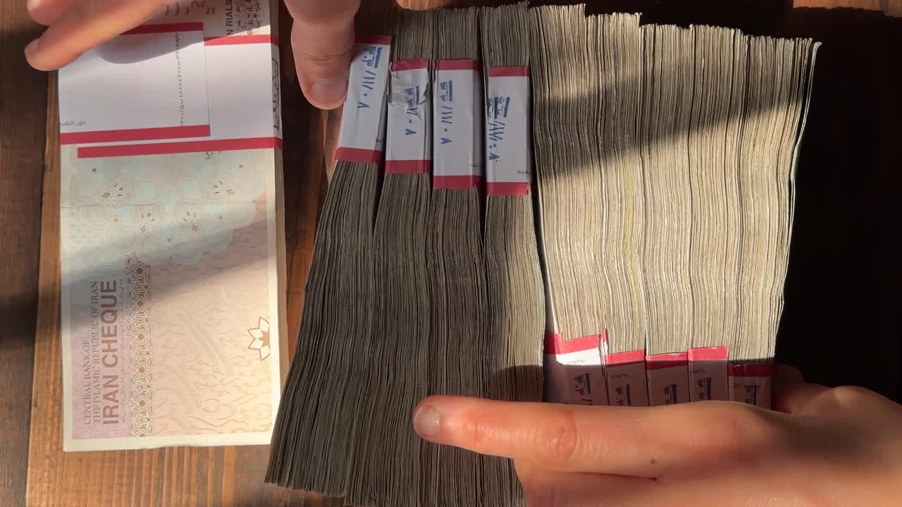 Counting Iran money bundle the biggest value banknote compare USD dollar daytime sun throw hurl forceful rial currency 100 bill versus financial fall inflation economy finance investment sell wealth
