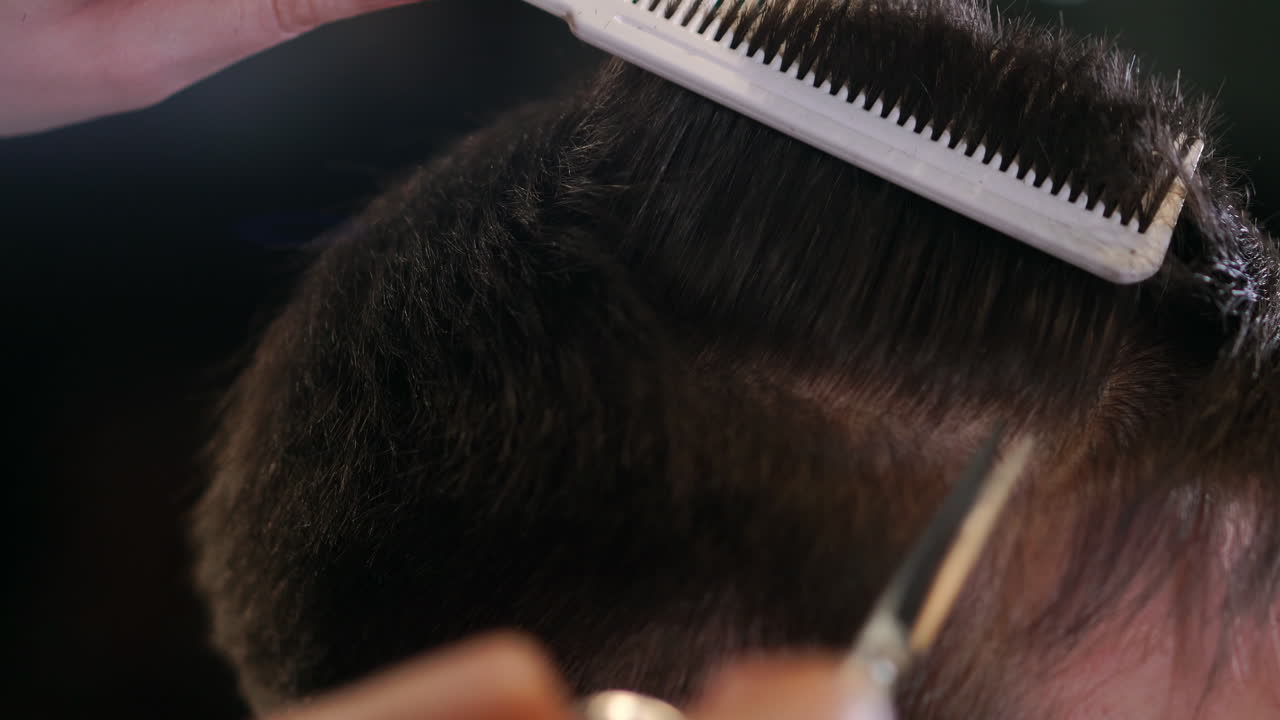 Close up of men's hair cutting scissors in a beauty salon. Frame. Close up of a haircut at a hair saloon. Professional barber styling hair of his client