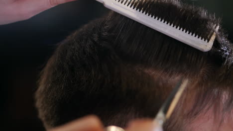 close up di uomini che tagliano i capelli con le forbici in un salone di bellezza. cornice. close up di un taglio di capelli in un salone di capelli. barbiere professionista che pettina i capelli del suo cliente