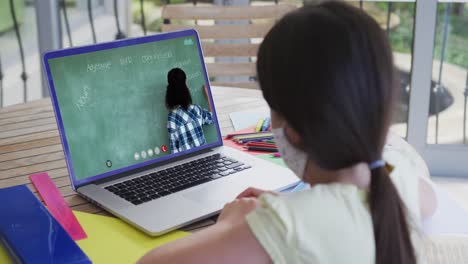 caucasian schoolgirl in face mask using laptop on video call with female teacher