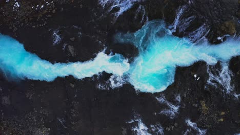 aerial descending shot of beautiful blue flowing bruarfoss waterfalls in iceland during daylight in iceland