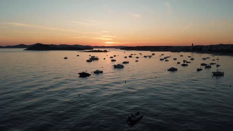 Drone-shot-of-coast-line-with-boats-in-the-water-with-sunset-in-the-background