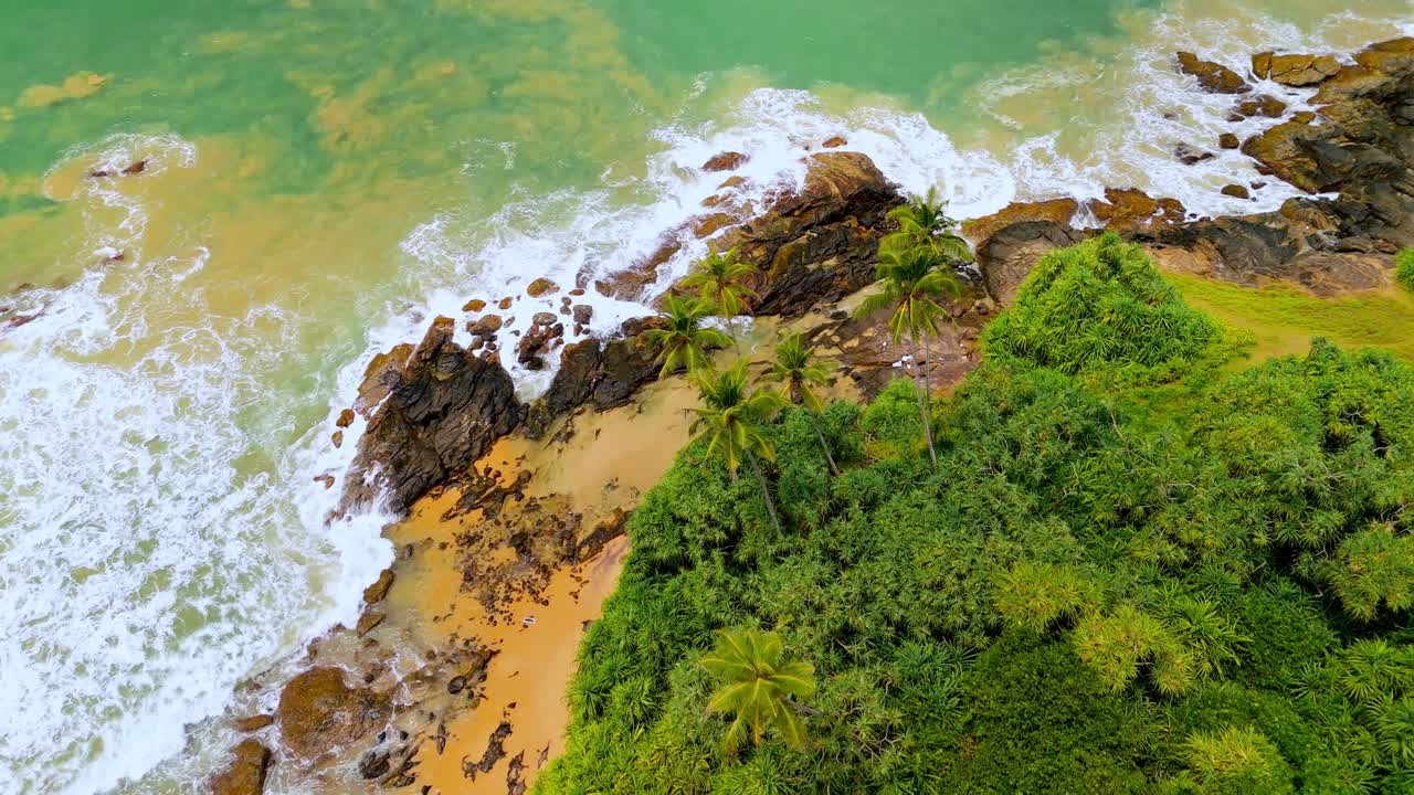 A breathtaking aerial drone shot of SK Town Surf Beach in Weligama, Sri Lanka, where lush jungle meets the ocean.