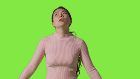 studio portrait of frustrated or angry woman standing against green screen 1