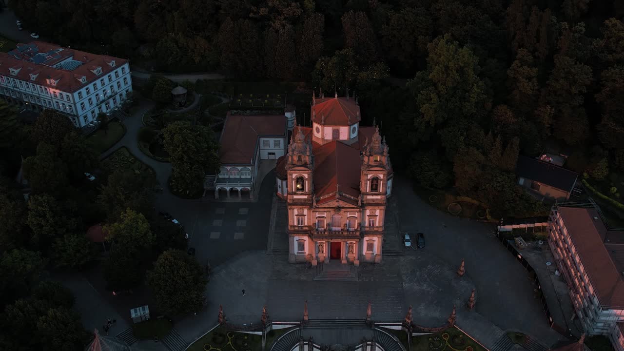 Bom Jesus do Monte Church illuminated during twilight, surrounded by dense forest. Braga Portugal