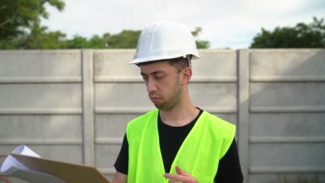 Un-Gerente,-Con-Un-Casco-Blanco,-Está-Evaluando-La-Información-Documentada-En-El-Portapapeles-(primer-Plano-Medio)