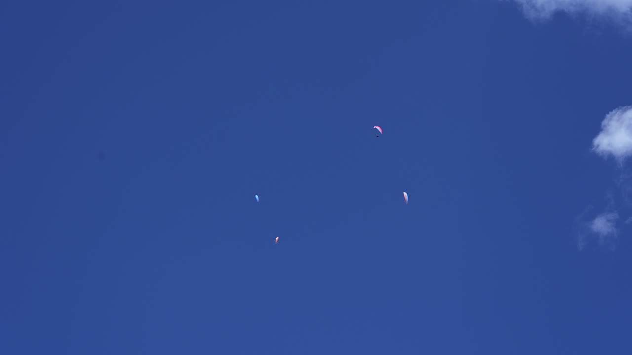 4개의 낙하산이 스위스 알프스, engelberg, obwalden 위로 약간의 구름과 함께 푸른 하늘 높이 날고 있습니다.